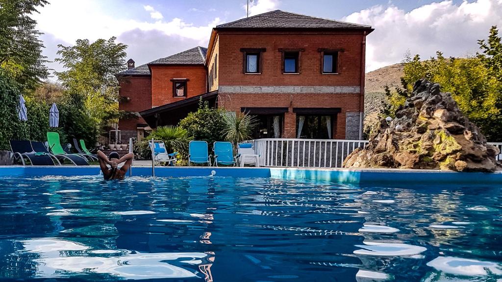 une personne dans l'eau d'une piscine dans l'établissement Hotel Rural Don Burguillo, à El Tiemblo