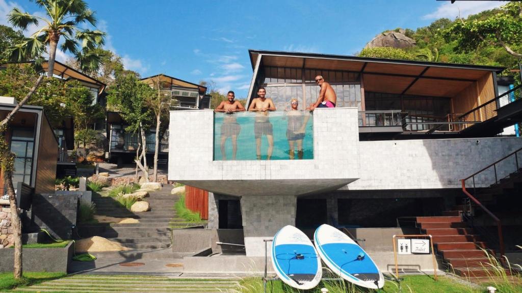 a group of people standing in a swimming pool with surfboards at The Cabin Beach Resort in Haad Rin