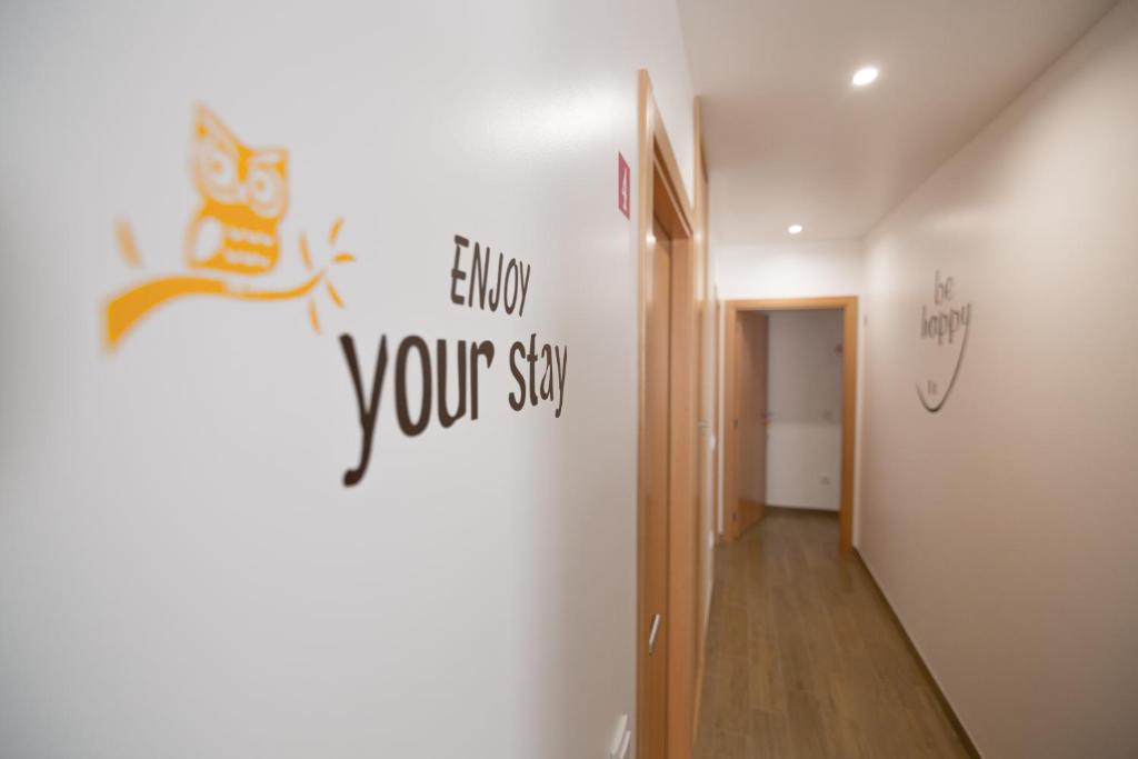 um corredor com uma parede com uma placa que lê siga a sua estadia em Mocho GuestHouse em São Mamede