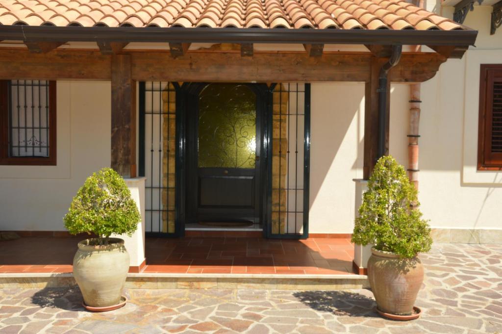 einer Haustür eines Hauses mit zwei Topfpflanzen in der Unterkunft Casa vacanza Borgo Parrini in Partinico