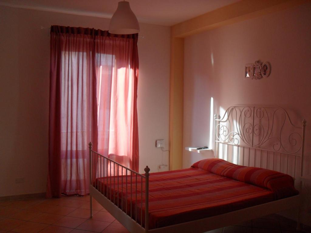 a bedroom with a red bed and a window at Casa Del Padrino in Ispica