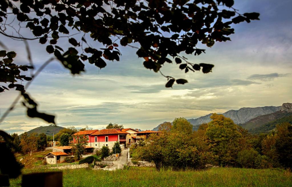 uma casa vermelha num campo com montanhas ao fundo em Casería el Hondrígu em Con