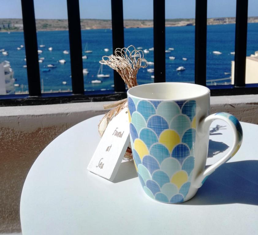 a coffee cup sitting on a table next to a window at No8 @ Seabreeze Court in Mellieħa