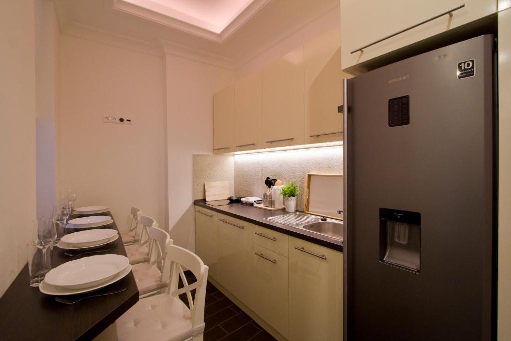 cocina con mesa, sillas y nevera en Elisabeth Bridge Apartmans, en Budapest