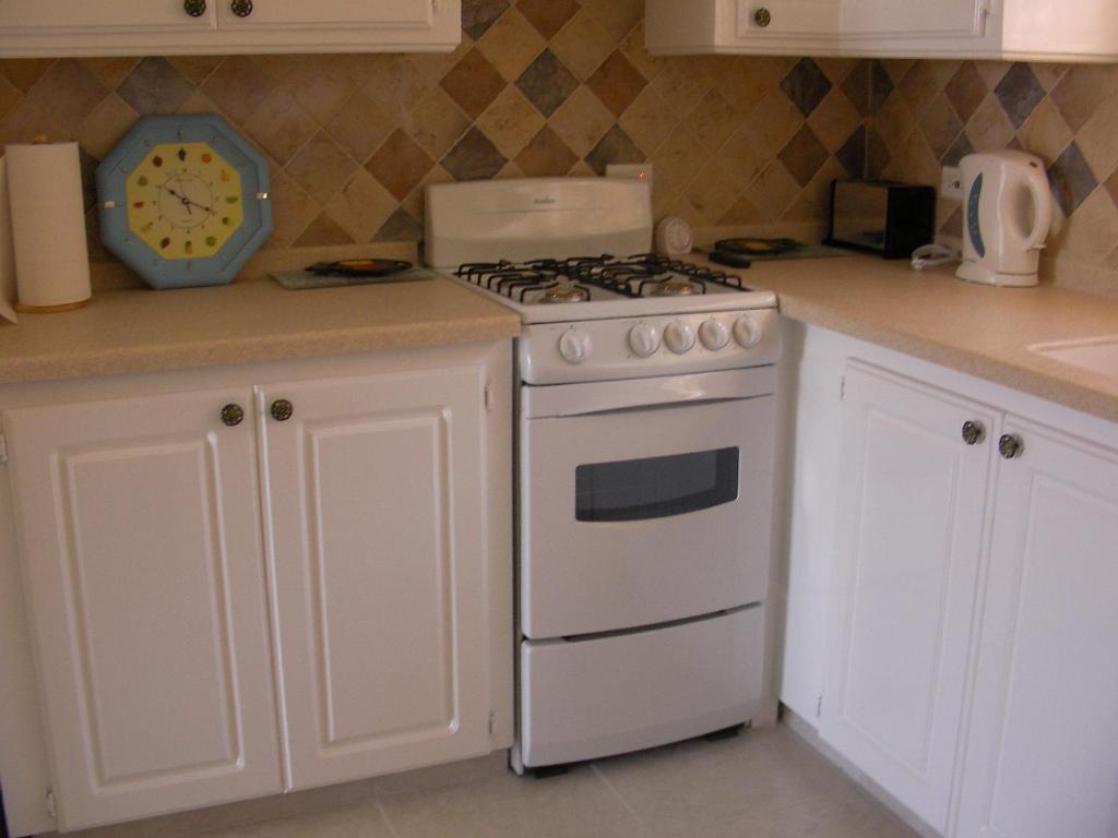 a kitchen with a stove and a clock on the counter at Plover Court Apartments in Christ Church