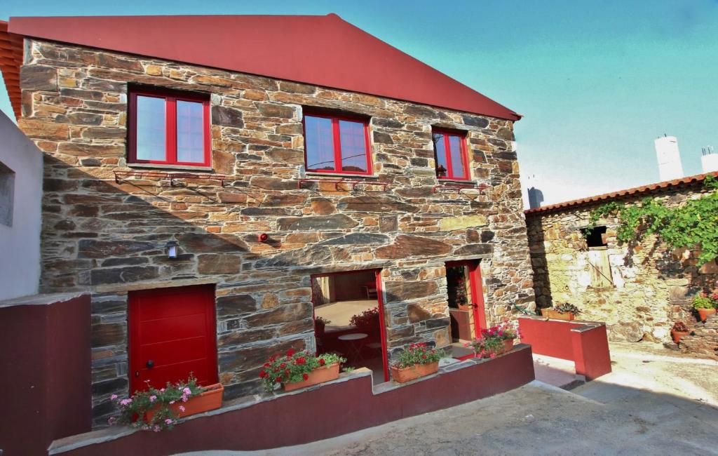 a stone house with red windows and red doors at Casa do Ocreza in Sobral Fernando