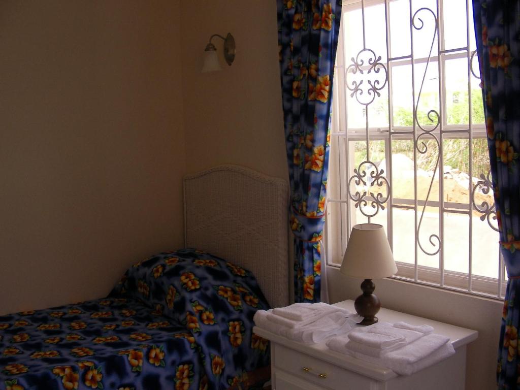 a small bedroom with a bed and a window at Plover Court Apartments in Christ Church