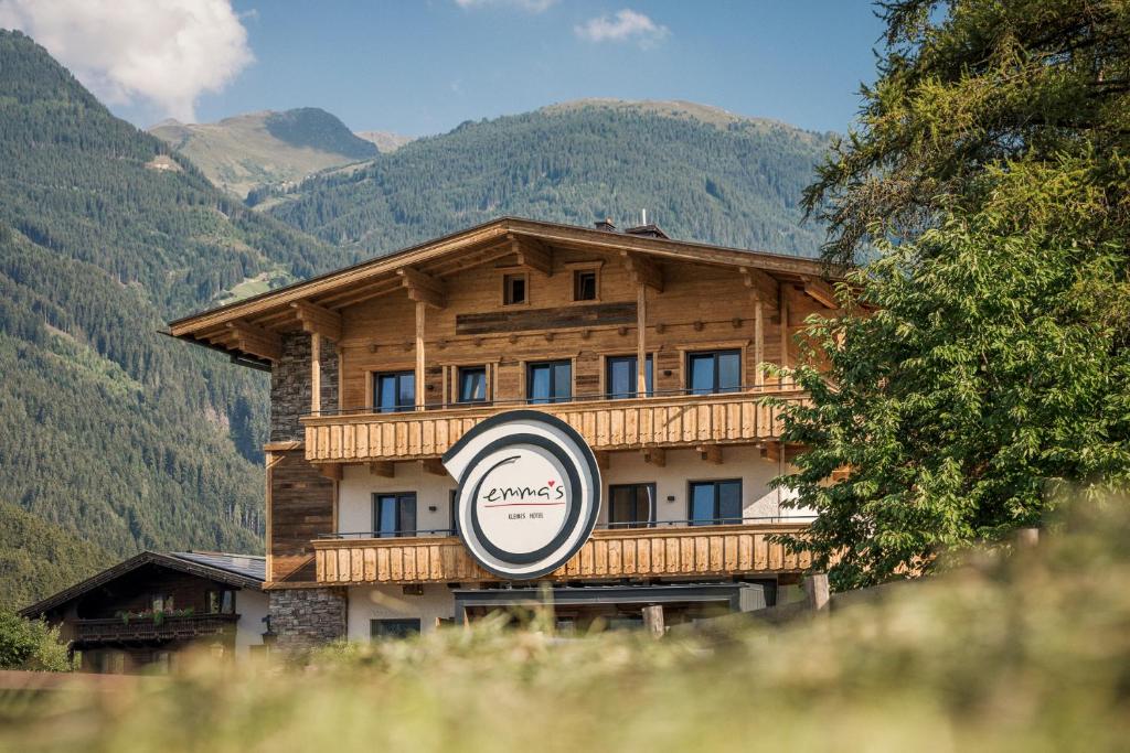 ein großes Holzgebäude mit einem Schild davor in der Unterkunft Emma's kleines Hotel in Ramsau im Zillertal