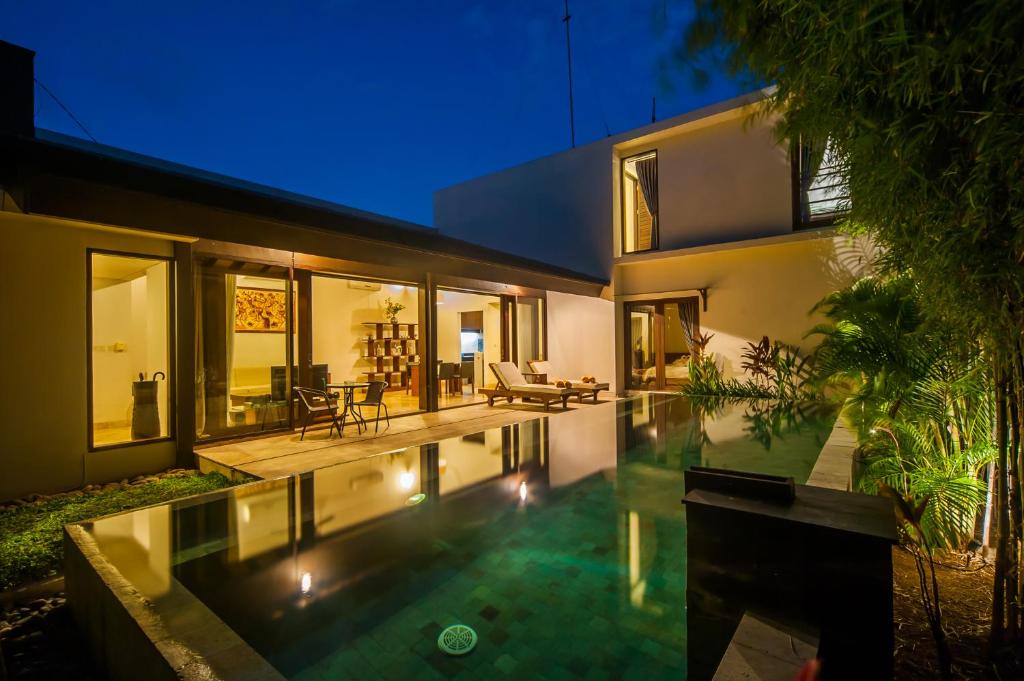 an external view of a house with a swimming pool at night at Tirta Villa in Sanur