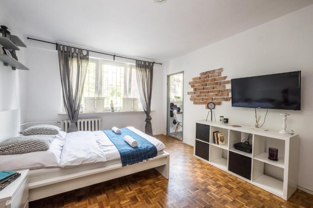 a bedroom with a bed and a flat screen tv at Noctis Apartment Powiśle in Warsaw