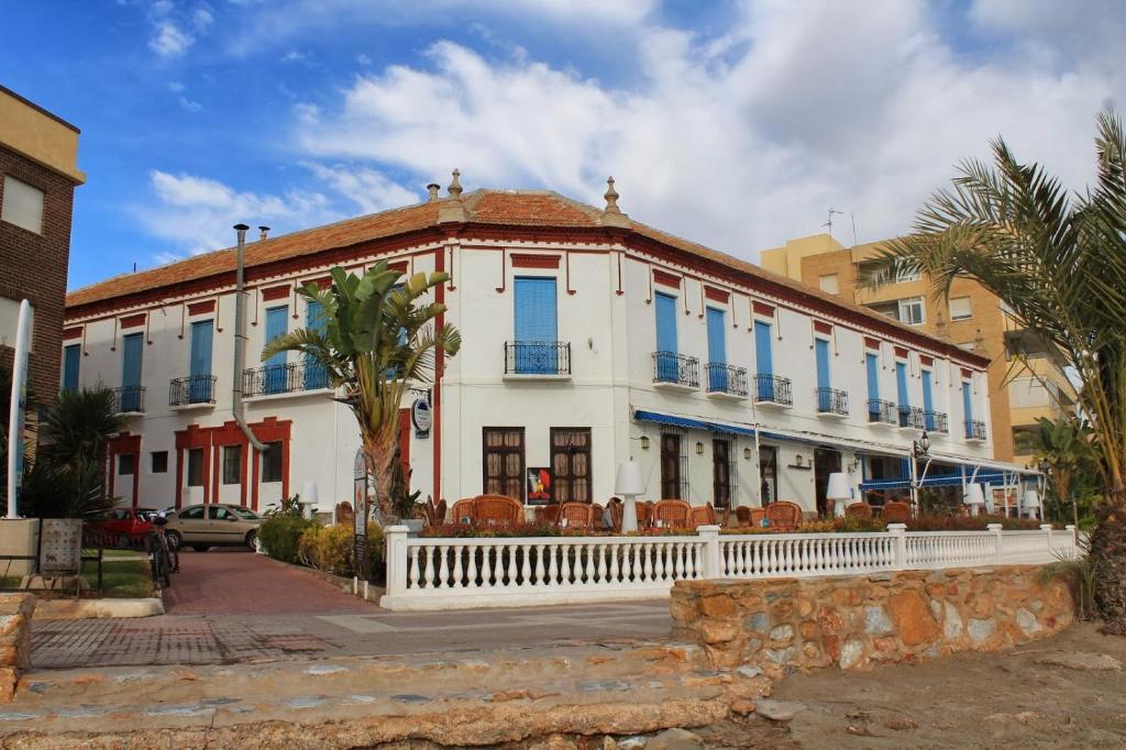 a white building with blue windows on a street at BALNEARIO LA ENCARNACIÓN in Los Alcázares