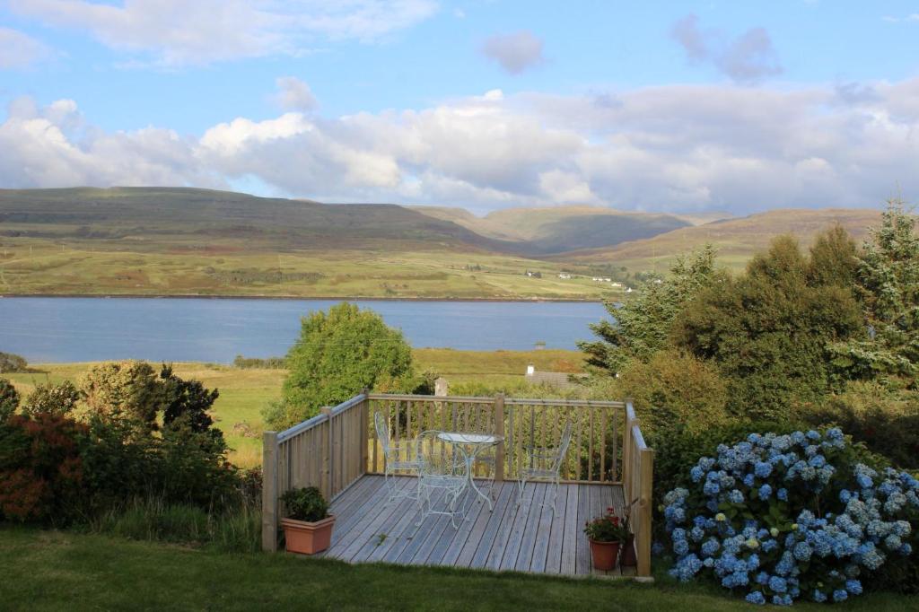 a wooden deck with flowers and a view of a lake at Sea Shimmer in Portree