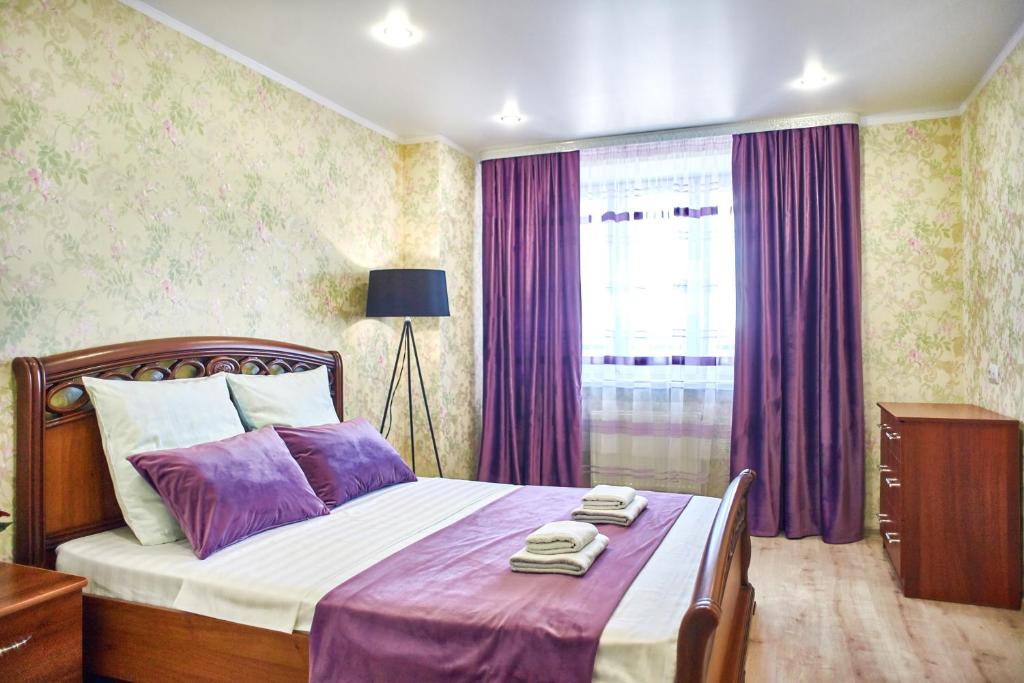 マグニトゴルスクにあるFive Stars River Sideのベッドルーム1室(紫のシーツが敷かれたベッド1台、窓付)