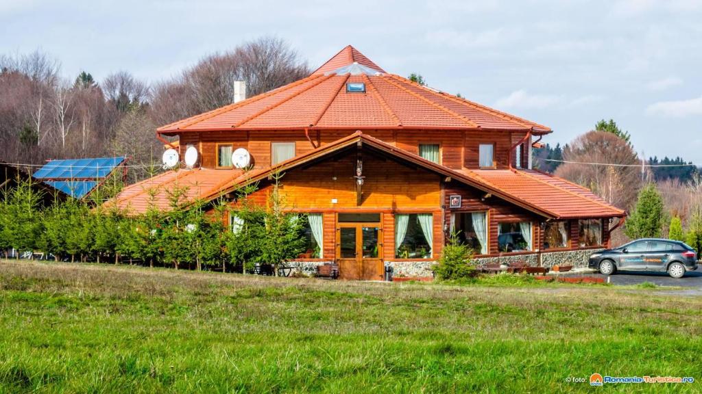 a large wooden house with an orange roof at Pensiunea Casa Zmeilor in Drăguş