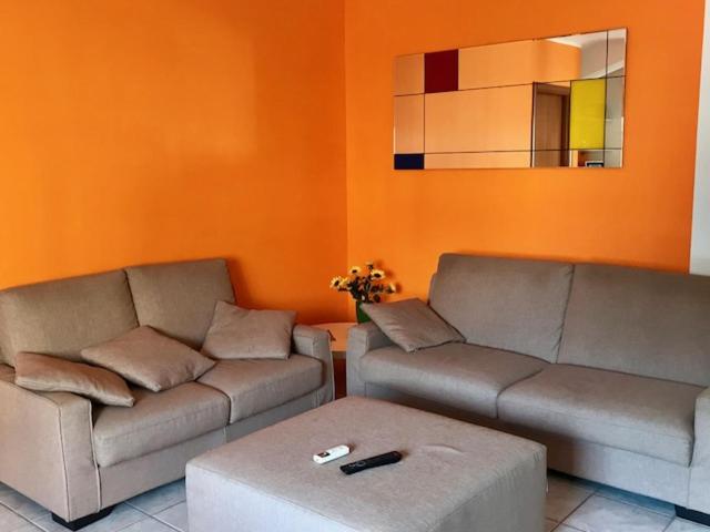 una sala de estar con 2 sofás y una pared de color naranja en B&B Il Girasole, en Rogliano
