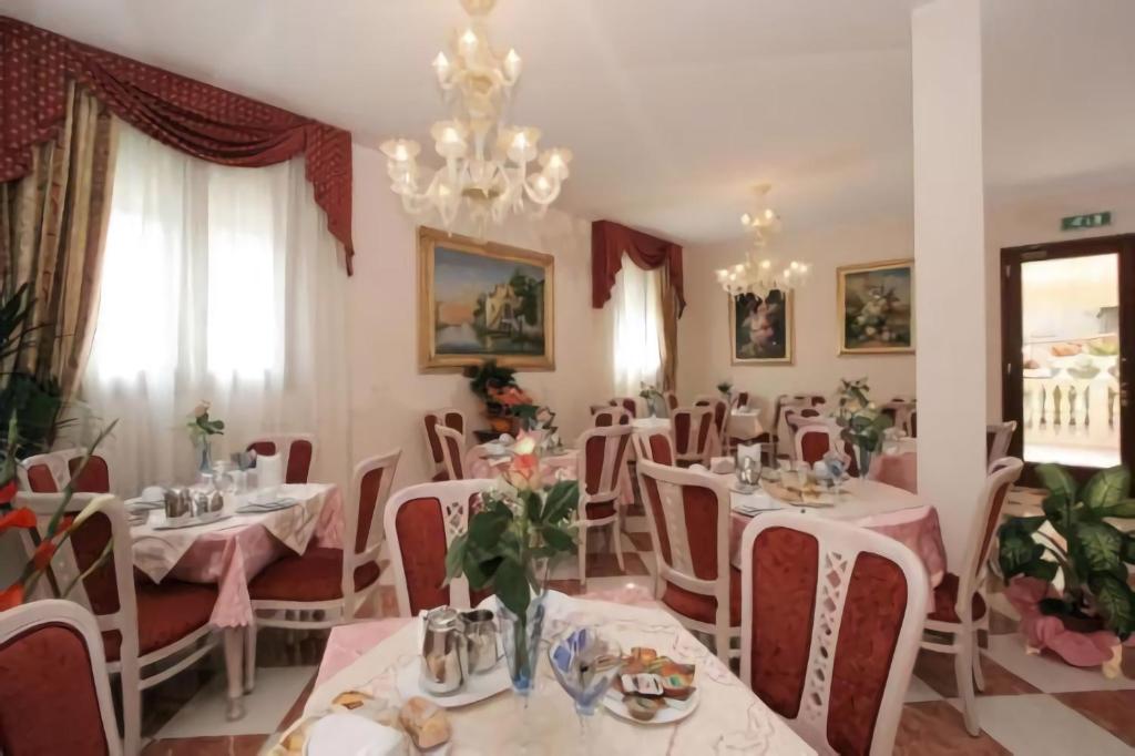 een restaurant met witte tafels en stoelen en een kroonluchter bij Nice Hotel in Marghera