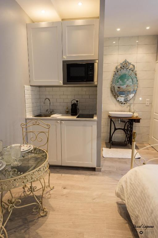 a kitchen with white cabinets and a table in a room at Cocoon amoureux de Beaune in Beaune