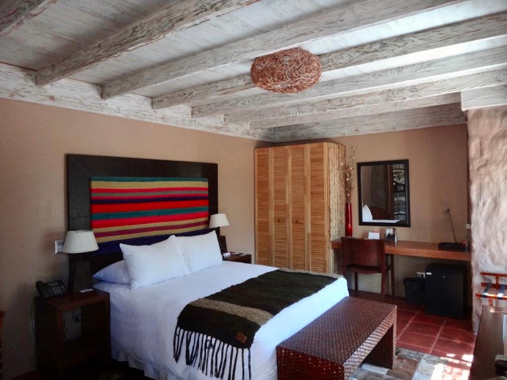 a bedroom with a large bed and a table and chair at Noi BordeLoa in Calama