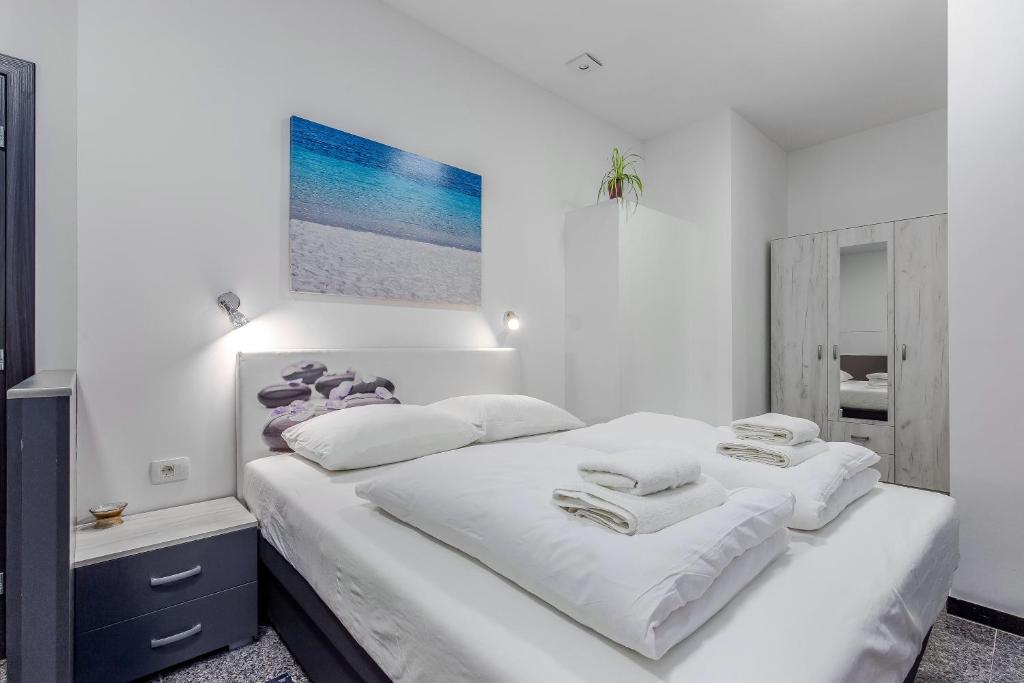ein weißes Schlafzimmer mit einem Bett mit weißer Bettwäsche und Handtüchern in der Unterkunft Apartments Black & White, Cherry & Blue in Rijeka