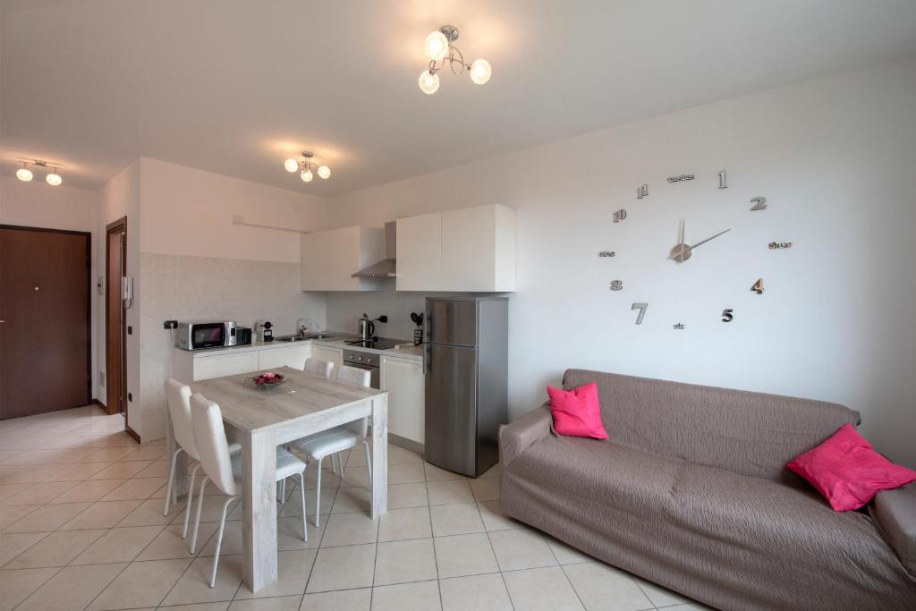 a living room with a couch and a table and a clock at Be Lake Apartment in Baveno