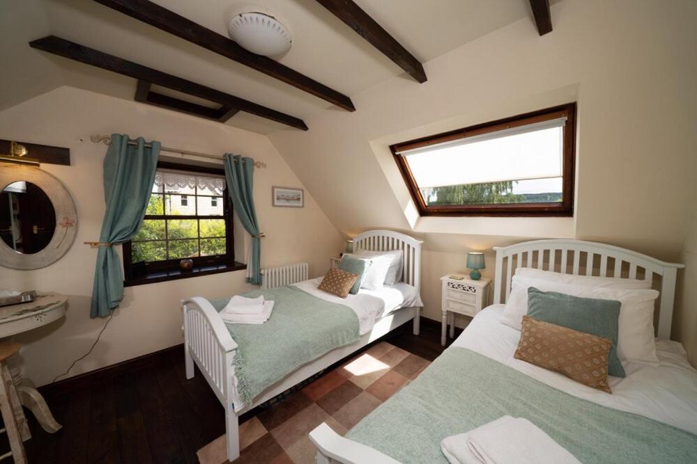 a bedroom with two beds and a sink and a mirror at The Old Coach House in Pitlochry