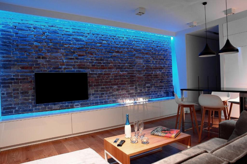 een woonkamer met een bakstenen muur en een tv bij Szopienicka Luxury in Katowice