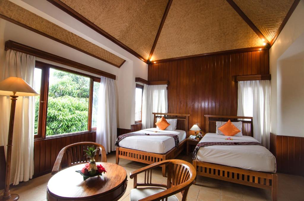 a bedroom with two beds and a table and chairs at Sri Phala Resort & Villa in Sanur