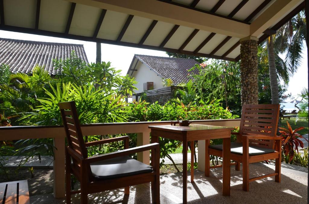 a patio with two chairs and a table on a porch at Cocotinos Sekotong Lombok in Sekotong
