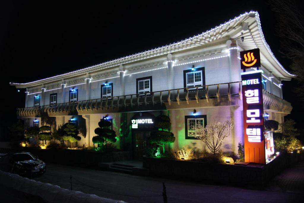 a white building with neon signs in front of it at Hill Motel in Gyeongju