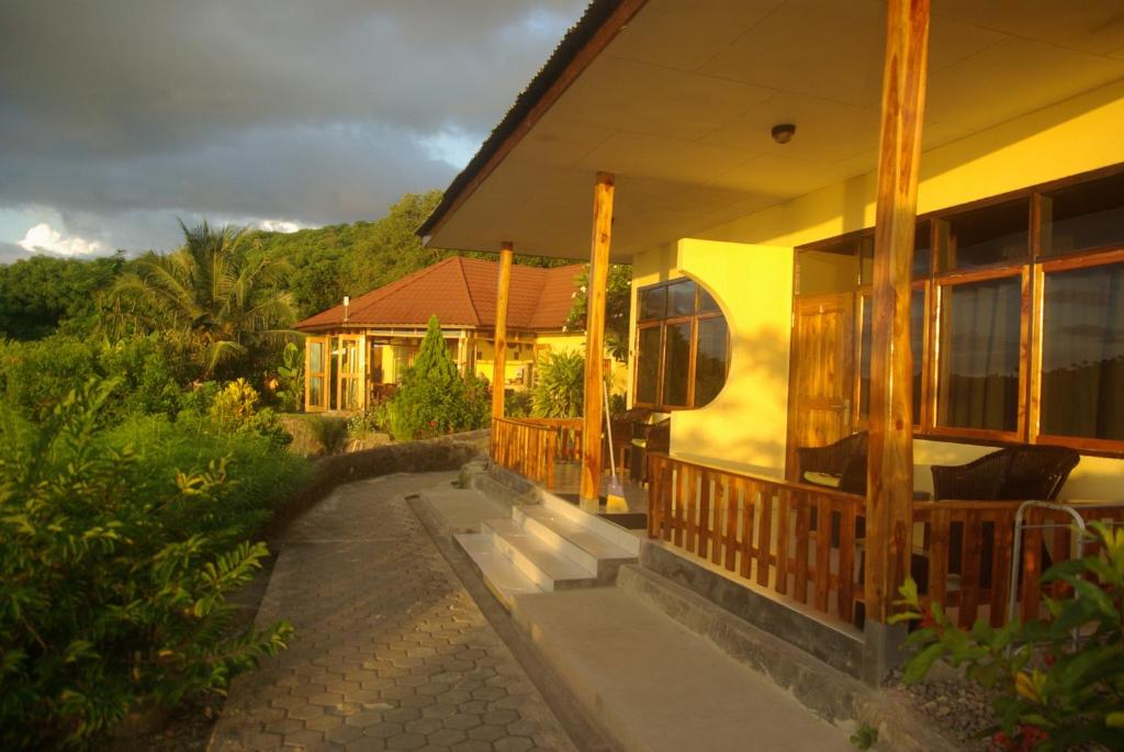 una casa amarilla con un camino que conduce a ella en Golo Hilltop Hotel, en Labuan Bajo