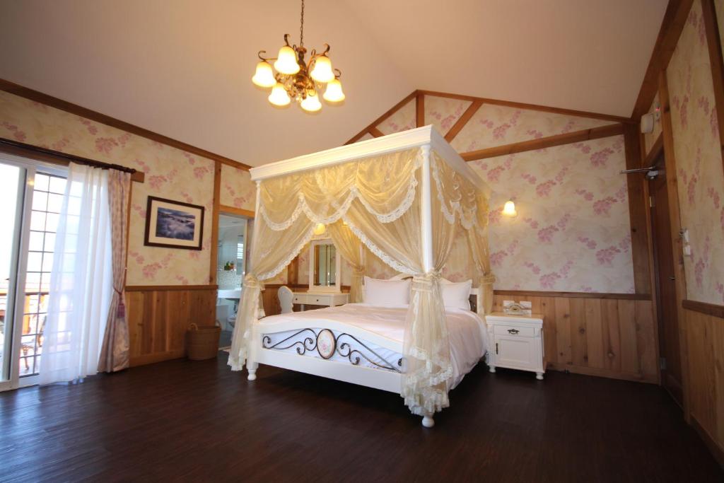 a bedroom with a canopy bed and a chandelier at Cingjing Vienna Pleasance Cottage in Ren&#39;ai