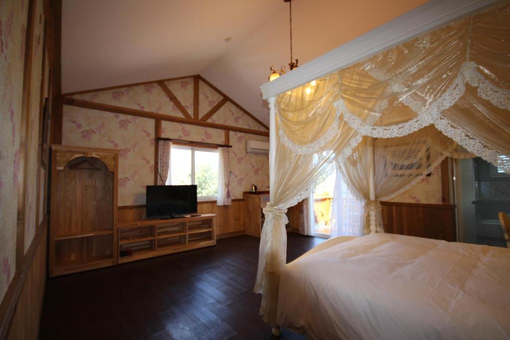 a bedroom with a canopy bed and a television at Cingjing Vienna Pleasance Cottage in Ren&#39;ai