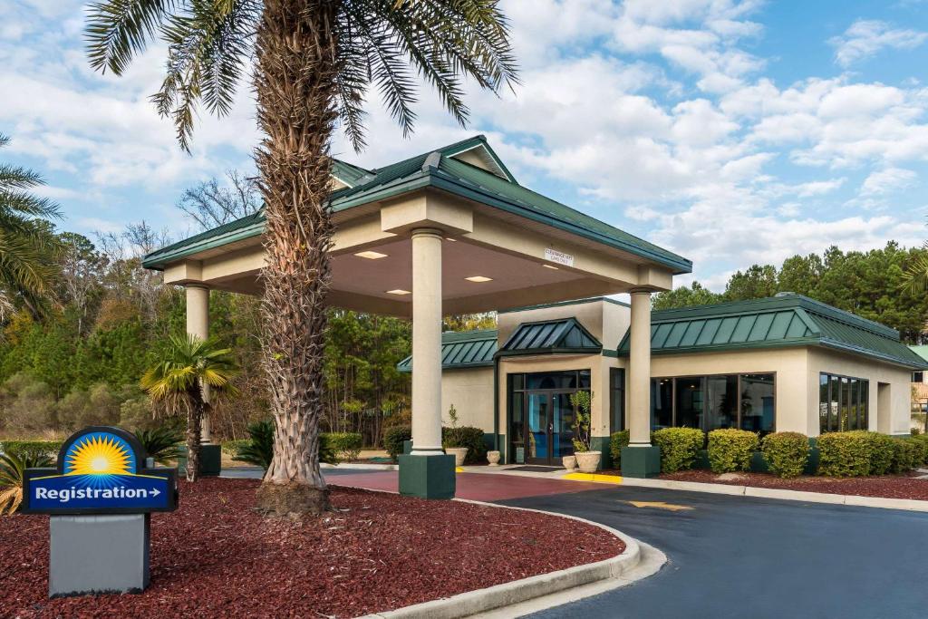 a hotel with a palm tree in front of a building at Days Inn by Wyndham Richmond Hill/Savannah in Richmond Hill