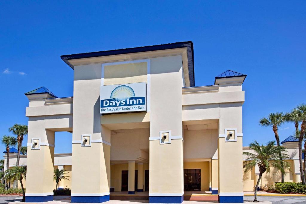 a large white building with a sign on the side of it at Days Inn by Wyndham Orlando Airport Florida Mall in Orlando