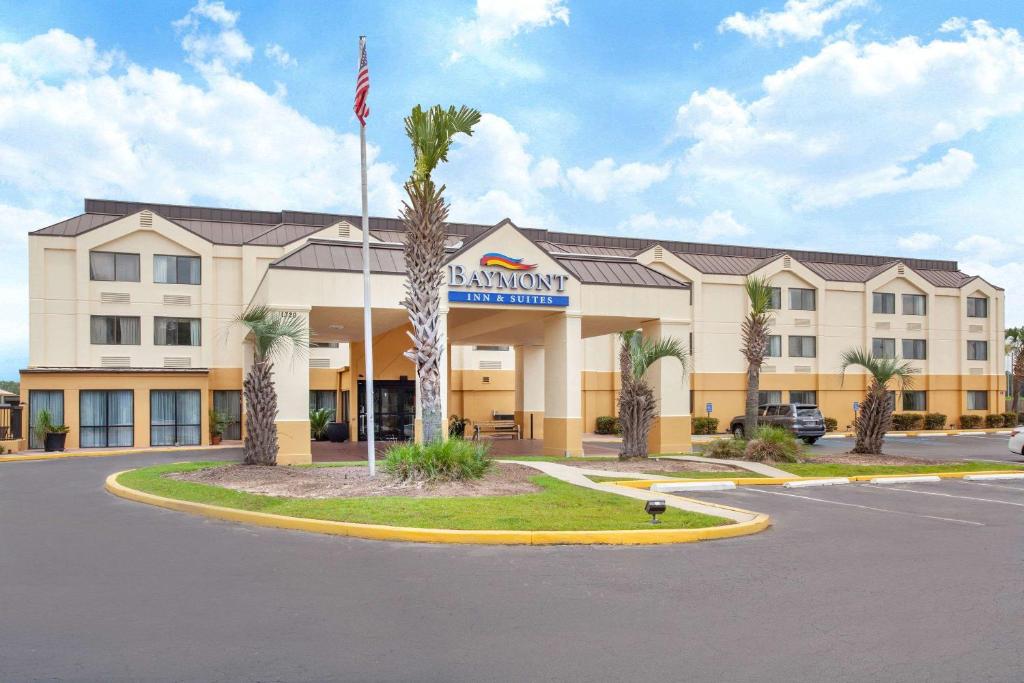 a hotel with a flag in front of a building at Baymont by Wyndham Saraland in Saraland