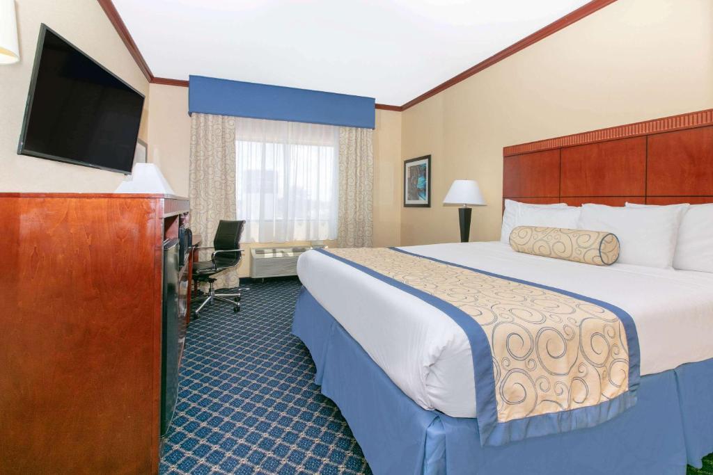 a hotel room with a bed and a flat screen tv at Baymont by Wyndham McComb in McComb