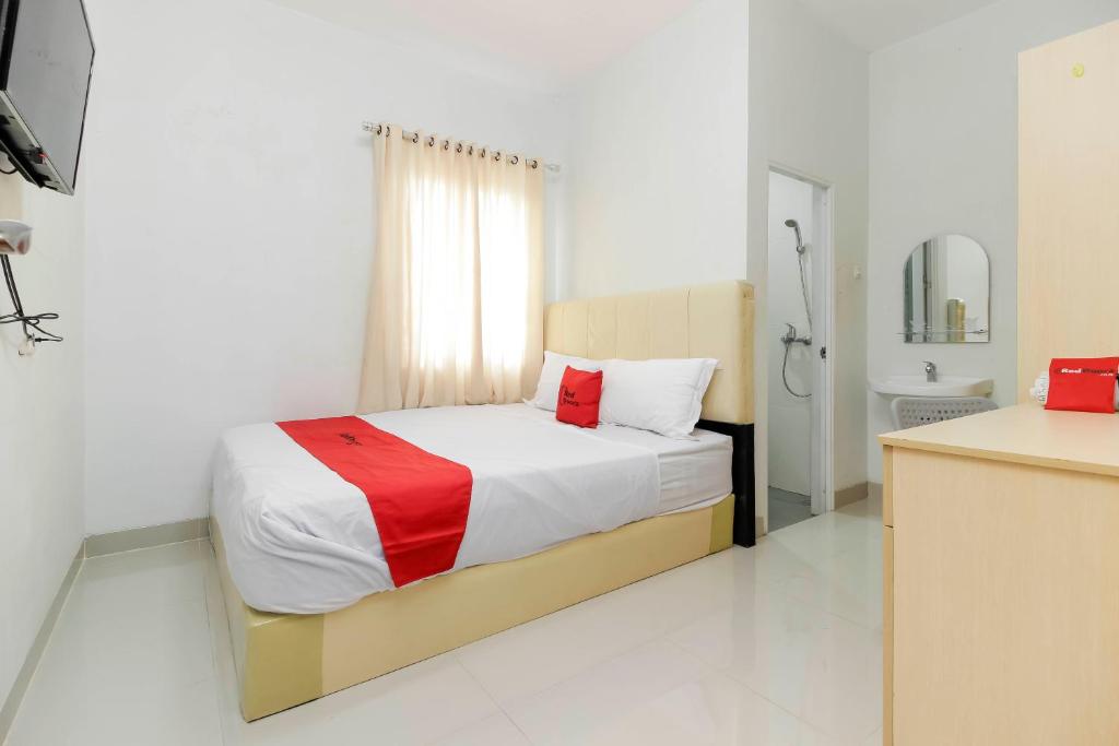 a bedroom with a bed and a bathroom with a sink at RedDoorz near Siloam Hospital Palembang in Palembang