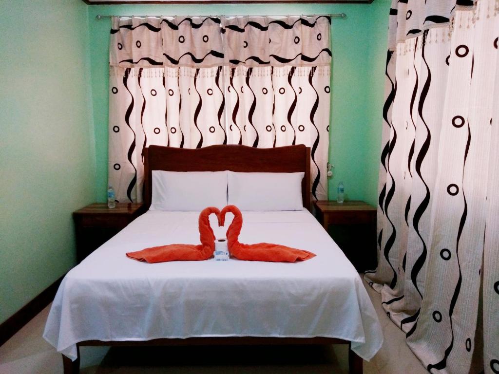 a bed with two red slippers on top of it at CHISIPHIL Homestay Port Barton in San Vicente