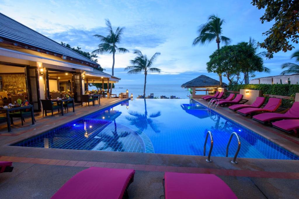 a pool with pink lounge chairs next to a resort at Samui Jasmine Resort - SHA Plus in Lamai