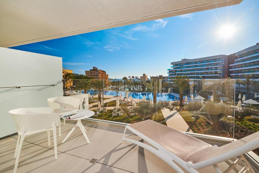 a balcony with white chairs and a large window at Hipotels Playa de Palma Palace&Spa in Playa de Palma