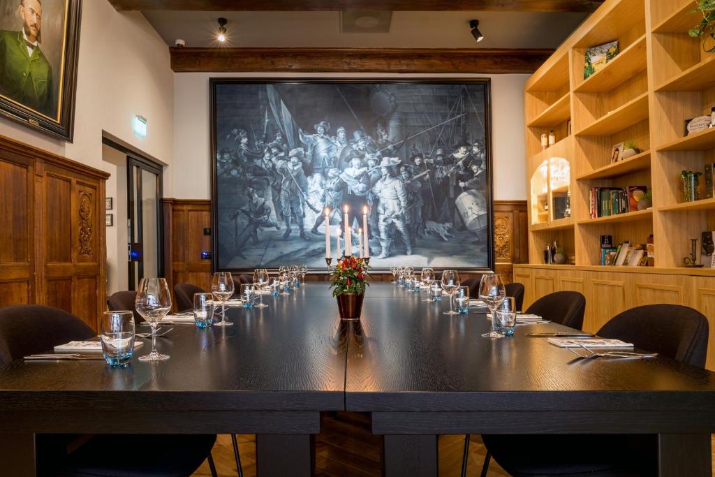 een tafel in een kamer met een groot schilderij aan de muur bij Hotel Die Port van Cleve in Amsterdam