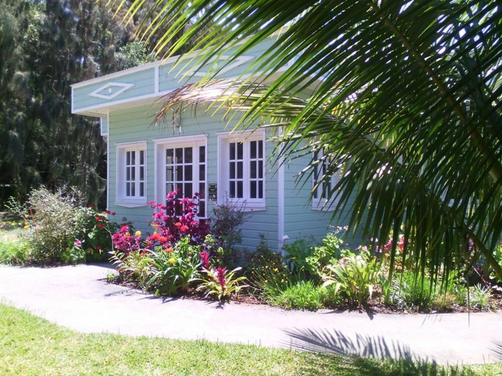 a small blue house with flowers in a garden at Le four à pain in Saint-Philippe