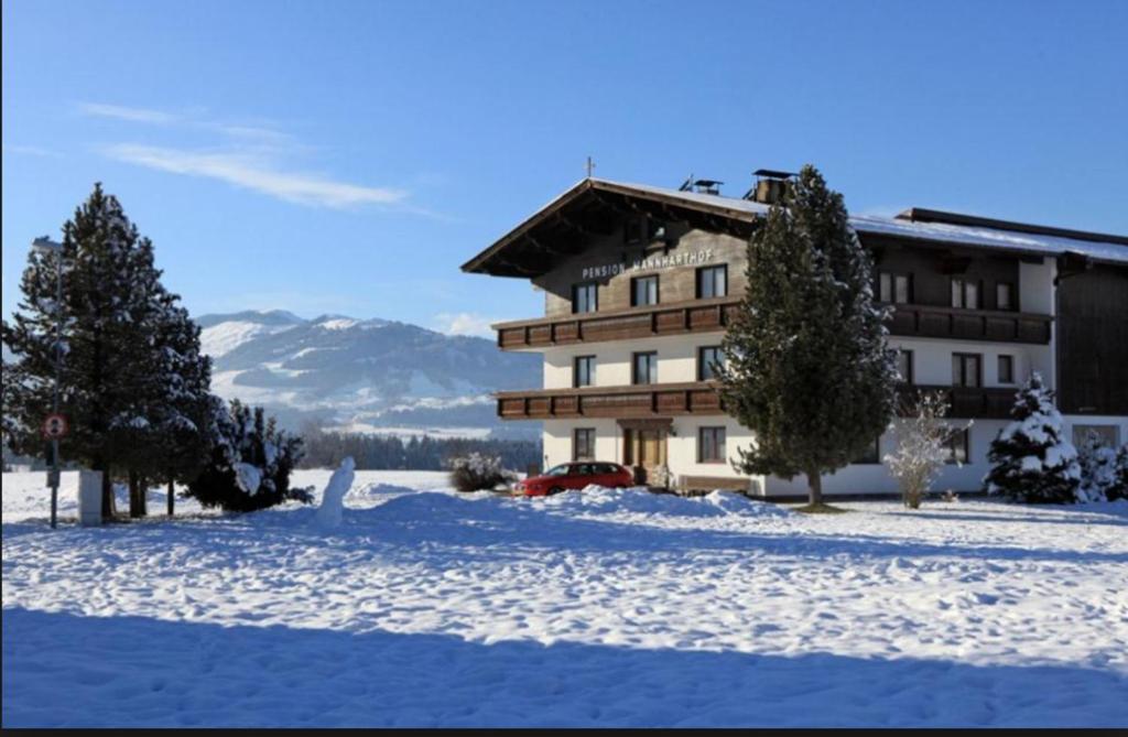 budynek w śniegu z drzewami przed nim w obiekcie Mannharthof w mieście Westendorf