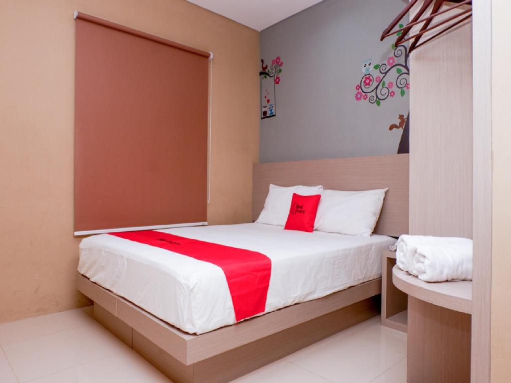 a bedroom with a bed with a red blanket at RedDoorz near Java Supermall Semarang in Semarang