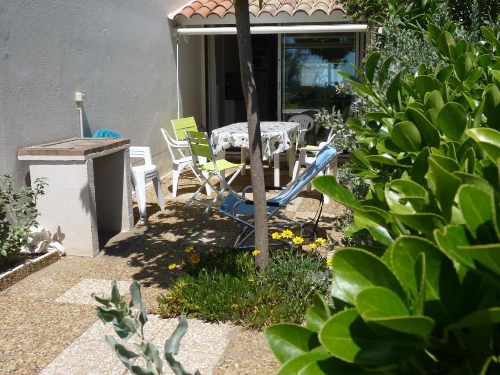 a patio with a table and chairs in a yard at Appartement T2 RDC, Front de Mer, 4 couchages, Les Balcons de la Méditerranée Narbonne Plage in Narbonne-Plage