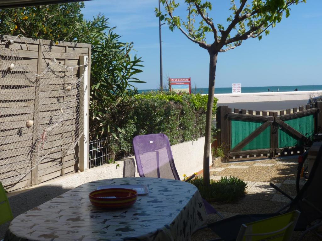 a table and a purple chair with a table and a fence at Appartement T2 RDC, Front de Mer, 4 couchages, Les Balcons de la Méditerranée Narbonne Plage in Narbonne-Plage