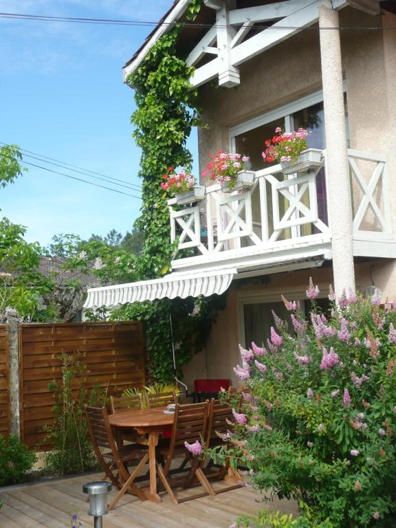a patio with a table and chairs and a balcony with flowers at Villa Le Mauret in Andernos-les-Bains