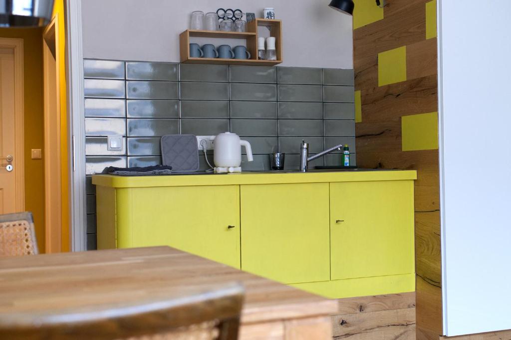 a yellow kitchen with a sink and a table at Momerooms – Appartement am Momering in Oberwesel