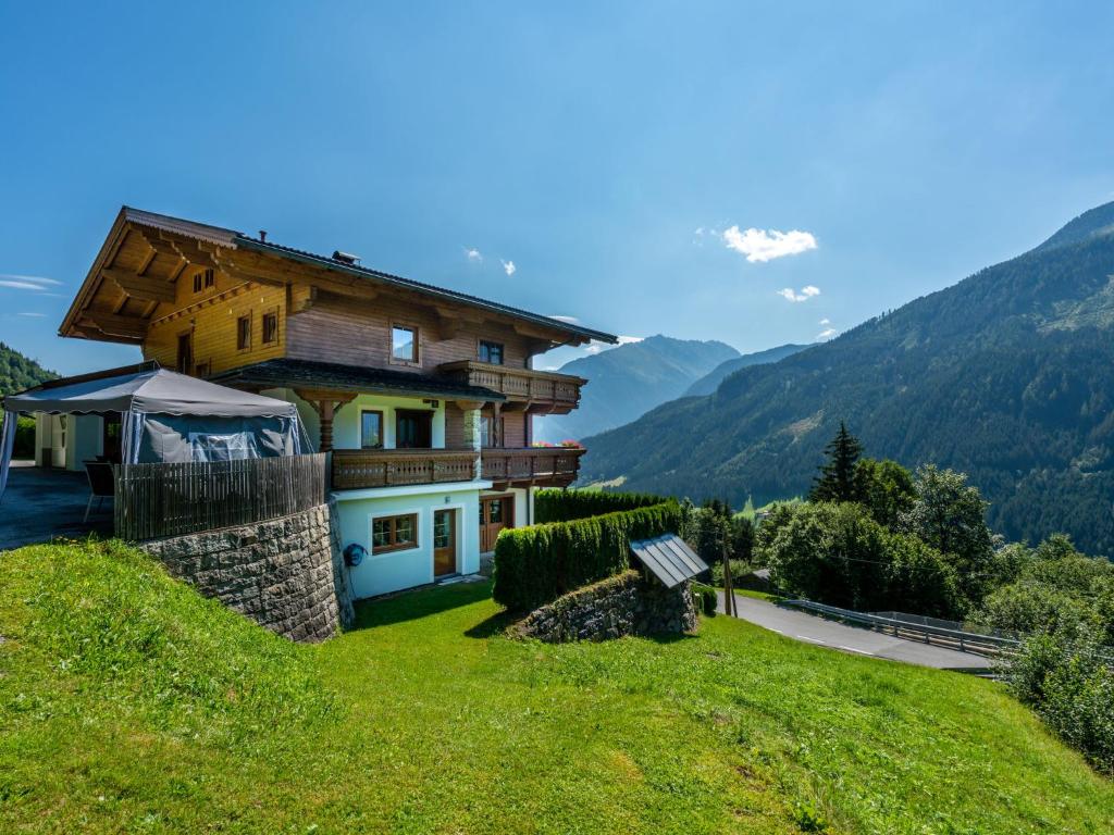 a house on a hill with mountains in the background at Cozy apartment with mountain views in Wald im Pinzgau