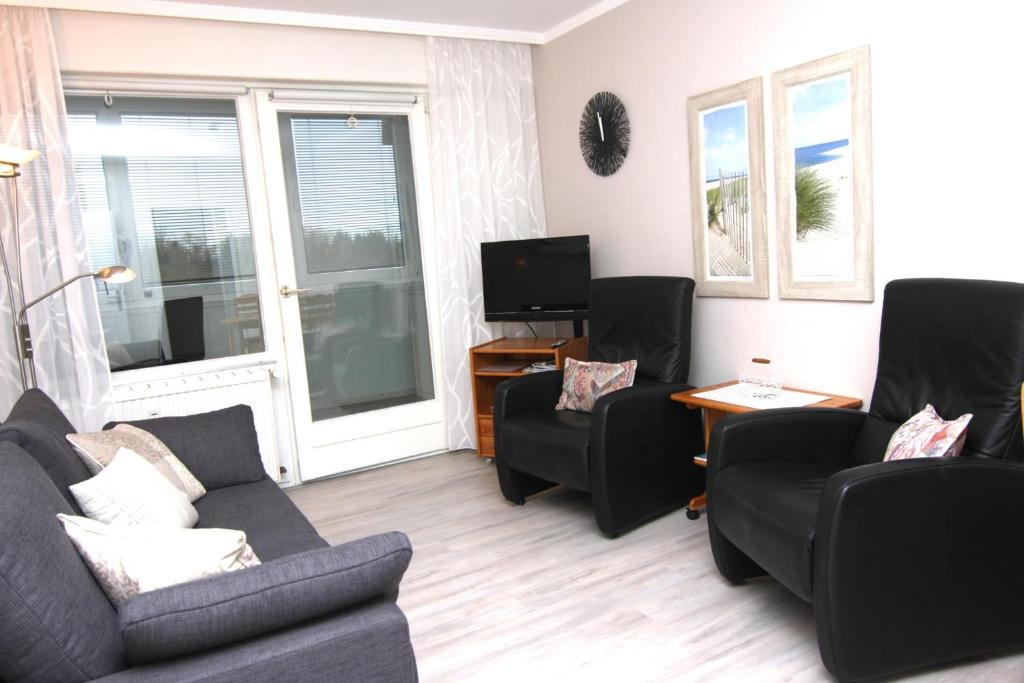 ein Wohnzimmer mit einem Sofa, Stühlen und einem TV in der Unterkunft Ferienwohnung F249 für 2-4 Personen an der Ostsee in Brasilien